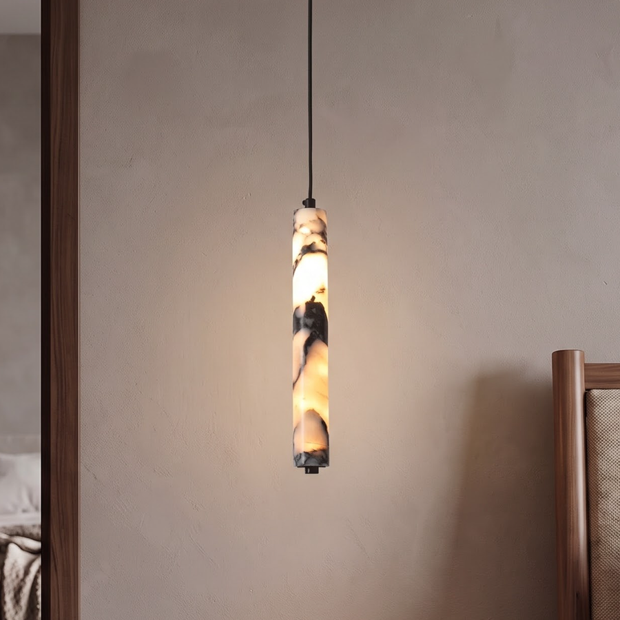 Slim veined stone cylinder pendant glowing beside a walnut nightstand