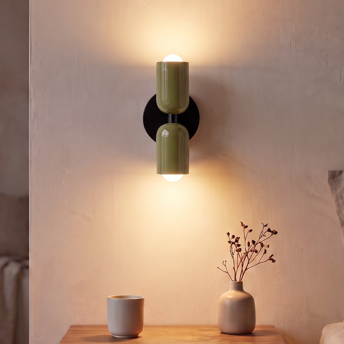 Olive green up and down wall sconce glowing above a nightstand