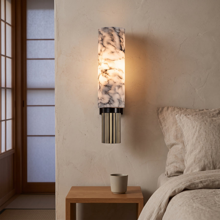 Marble and brass wall sconce lit beside a bed in a Japandi bedroom
