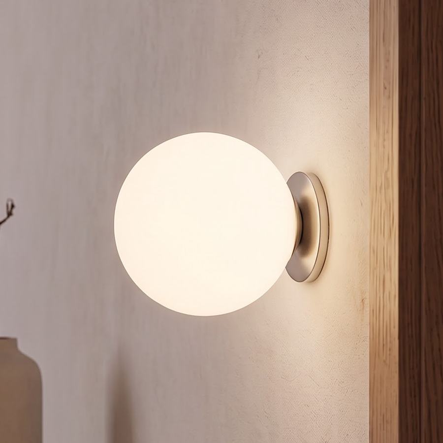 Frosted white glass globe wall sconce glowing beside an oak door frame
