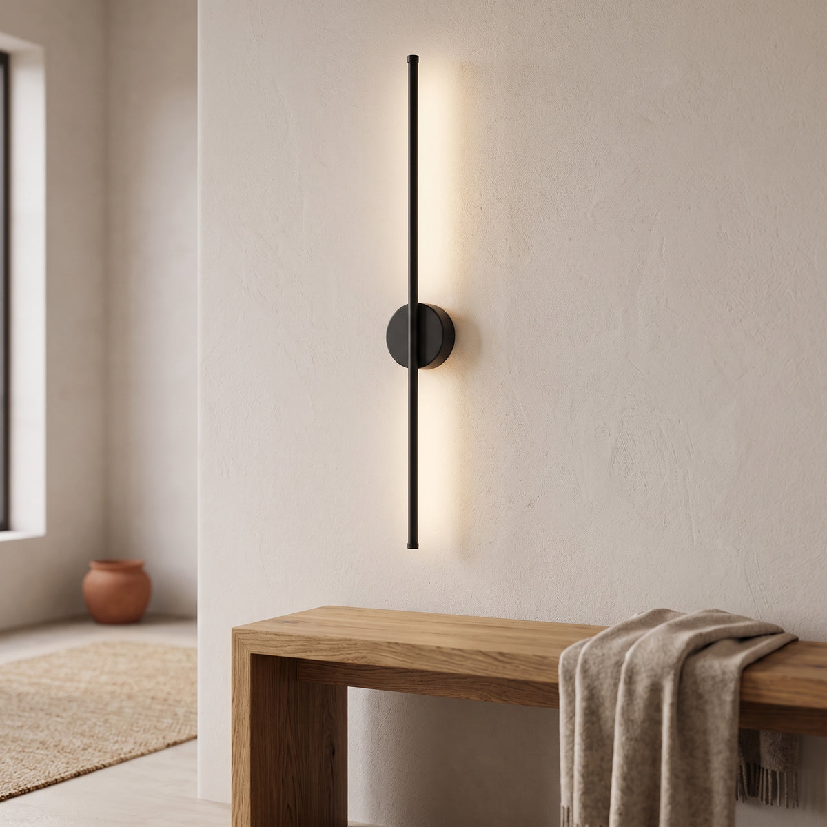 Black minimalist rod wall sconce in a warm white entry hallway