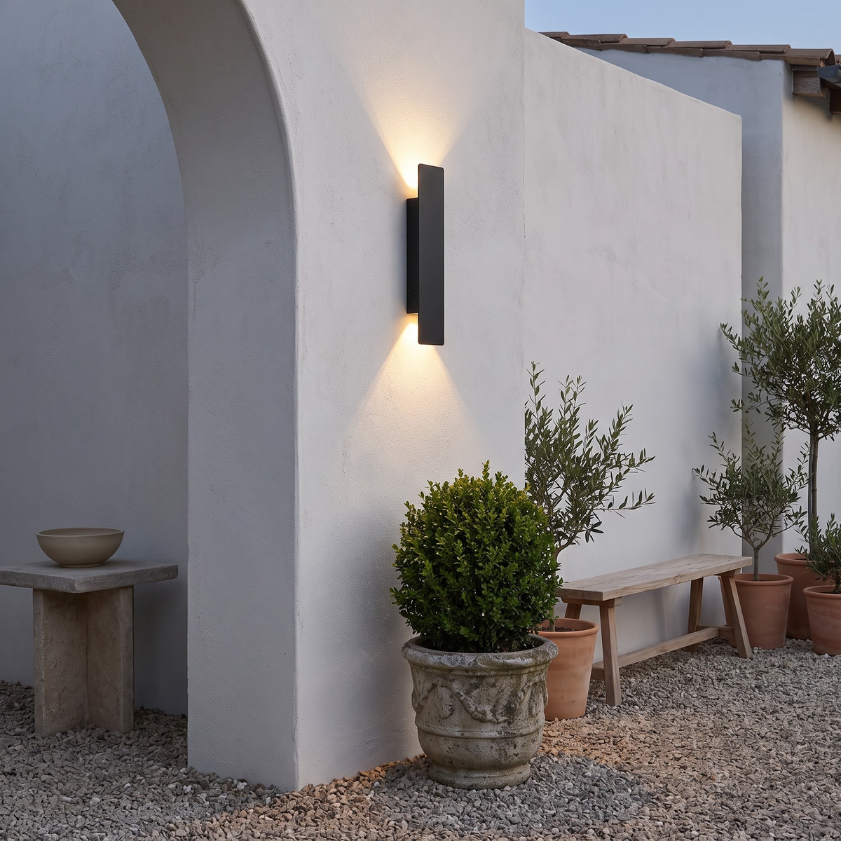 Black outdoor up-down wall light on a white stucco courtyard wall