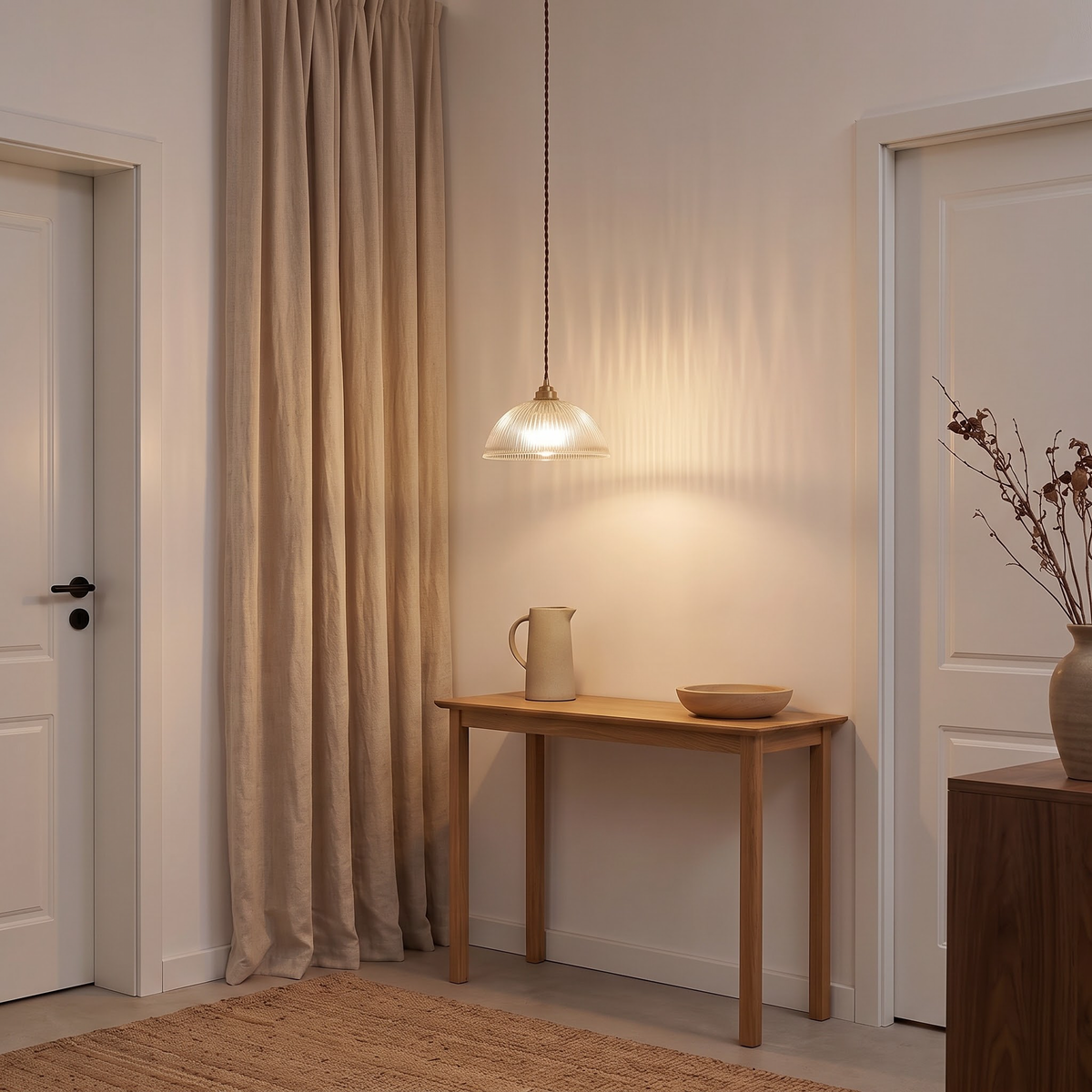 Clear fluted glass pendant over an oak console beside linen curtains