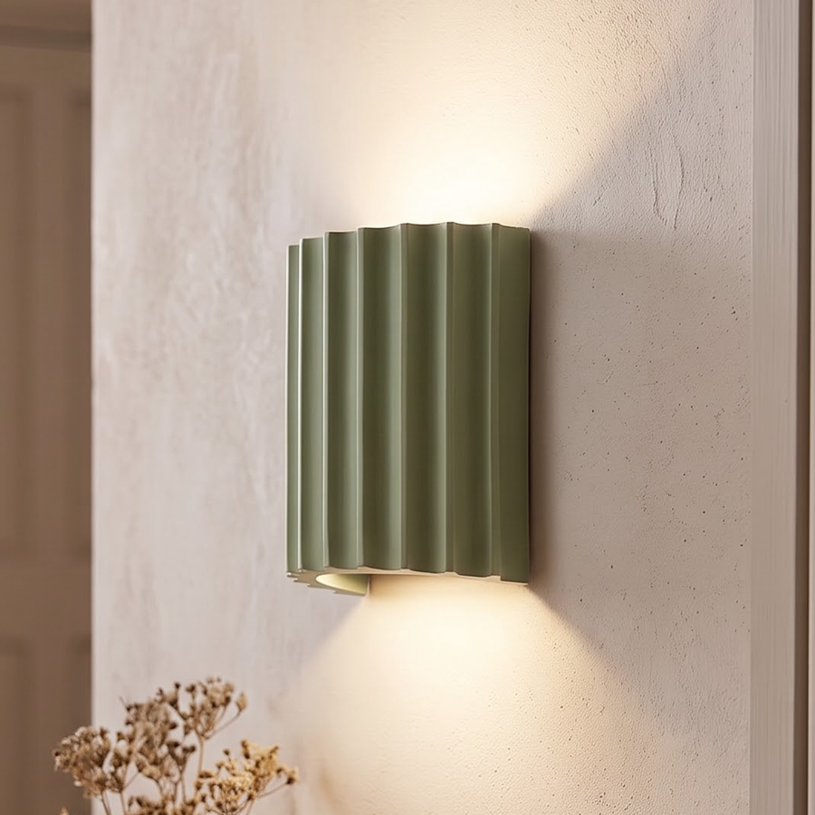 Sage green fluted wall sconce washing light up and down a plaster wall