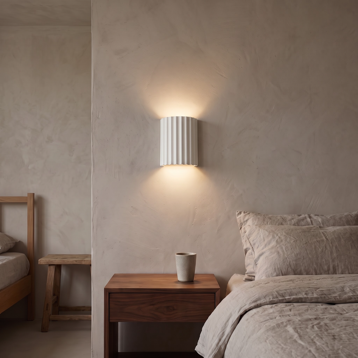 White fluted resin wall light above a walnut nightstand in a bedroom