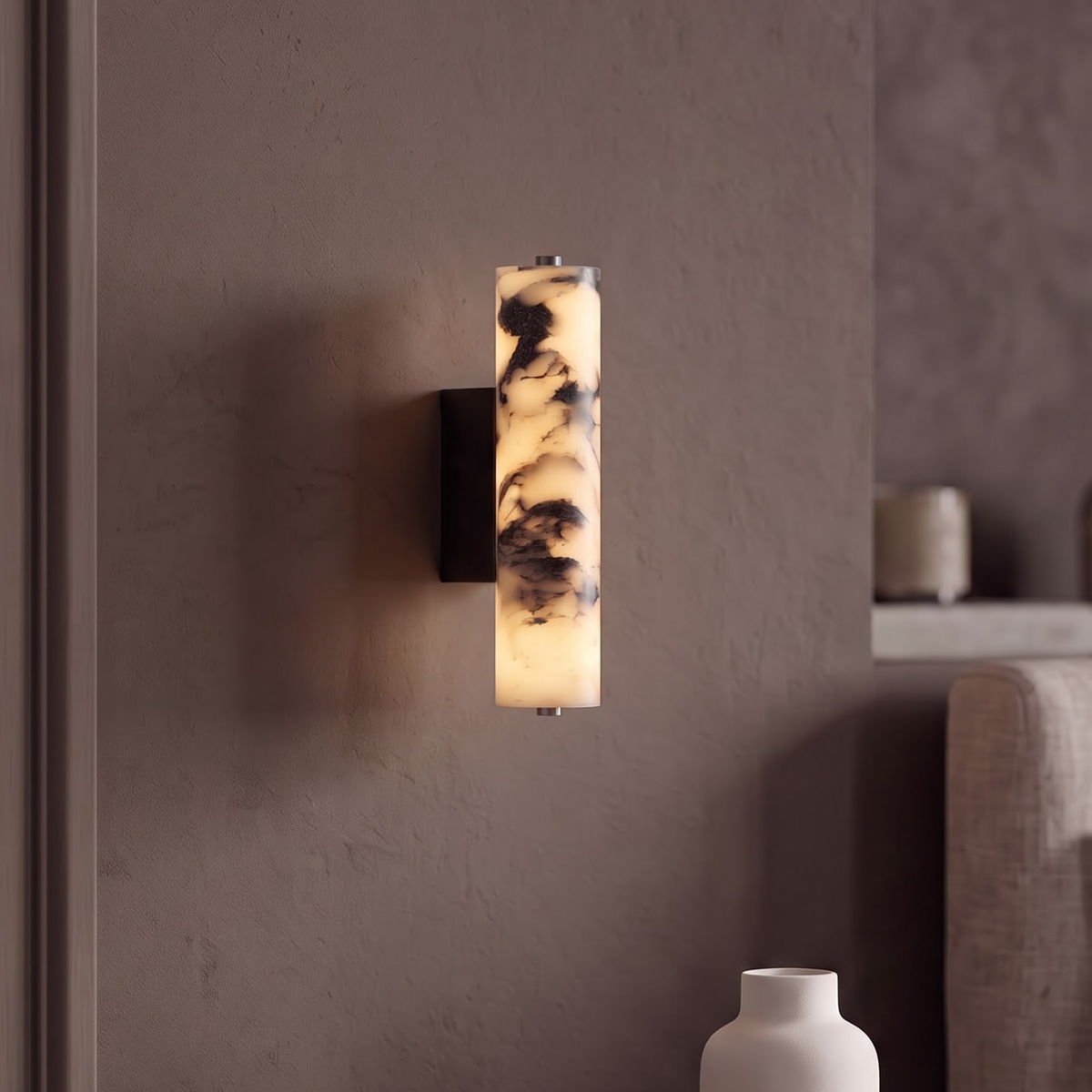 Slim veined stone cylinder wall sconce glowing beside a bedroom door