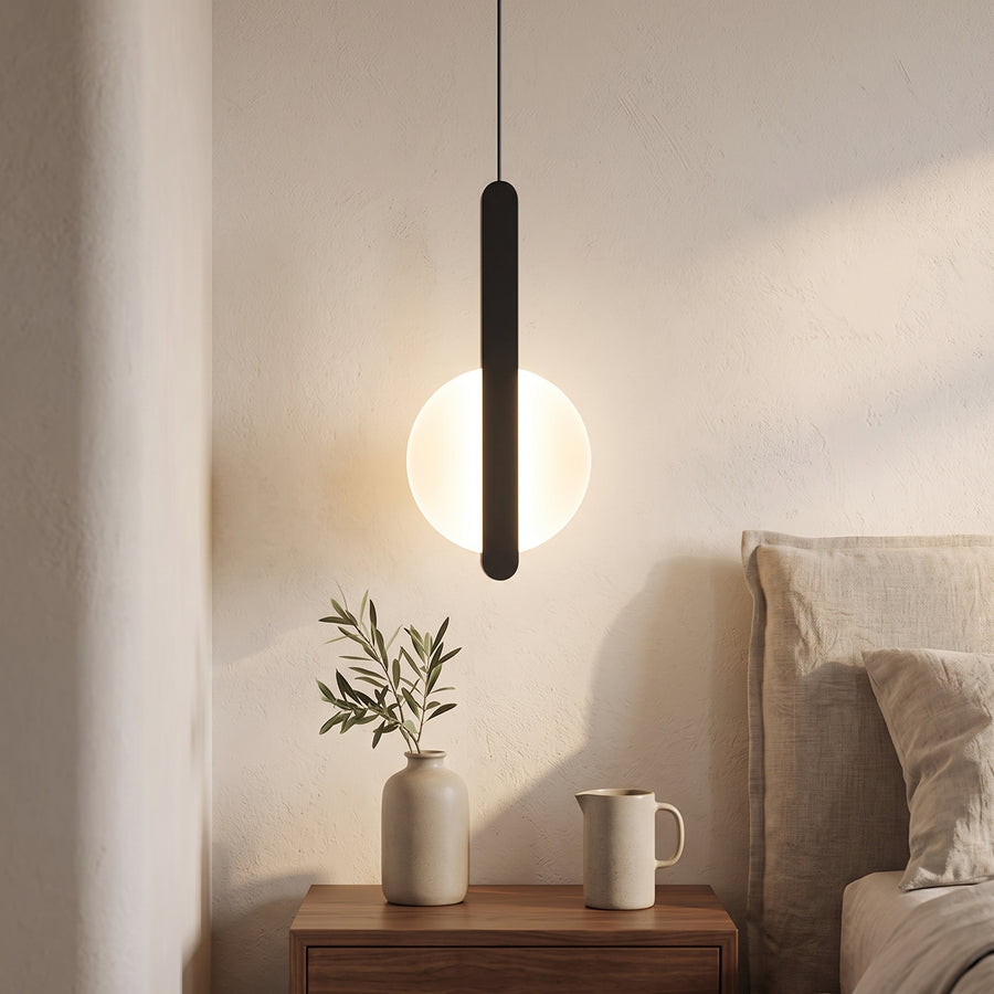 Black U-bar pendant with glowing opal disc above a walnut nightstand