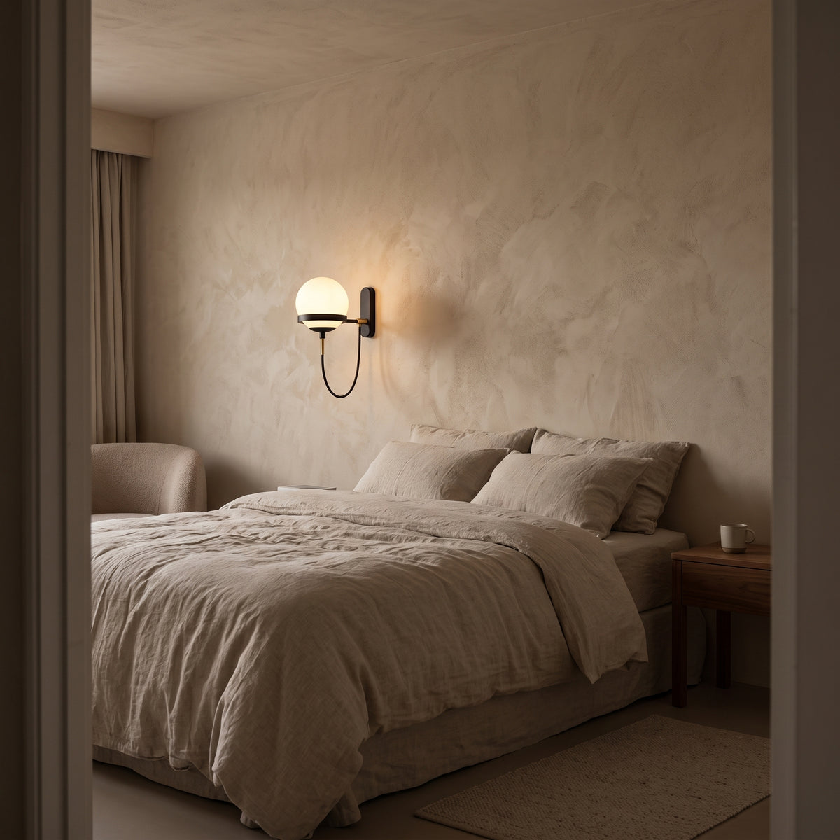 Black opal globe wall light beside a linen bed in a plaster bedroom