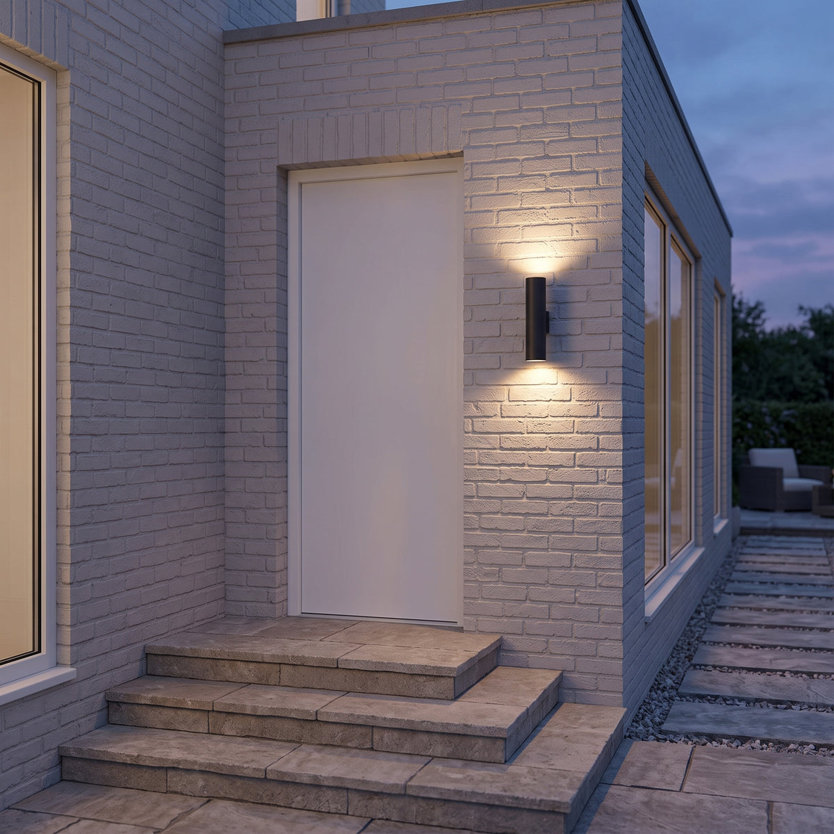 Toki black outdoor cylinder light washing a white brick wall by the door