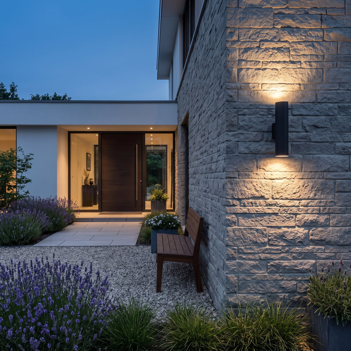Toki outdoor wall sconce lighting a stone wall beside a gravel terrace