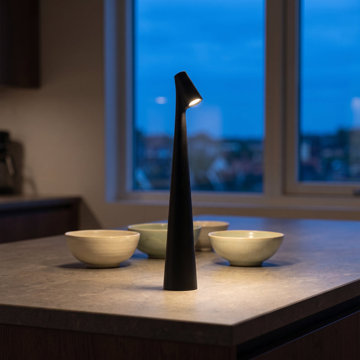 Black cordless table lamp on a stone kitchen island at blue hour