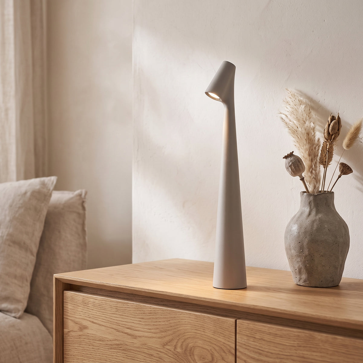 Gray slim cordless table lamp glowing on an oak sideboard beside a ceramic vase