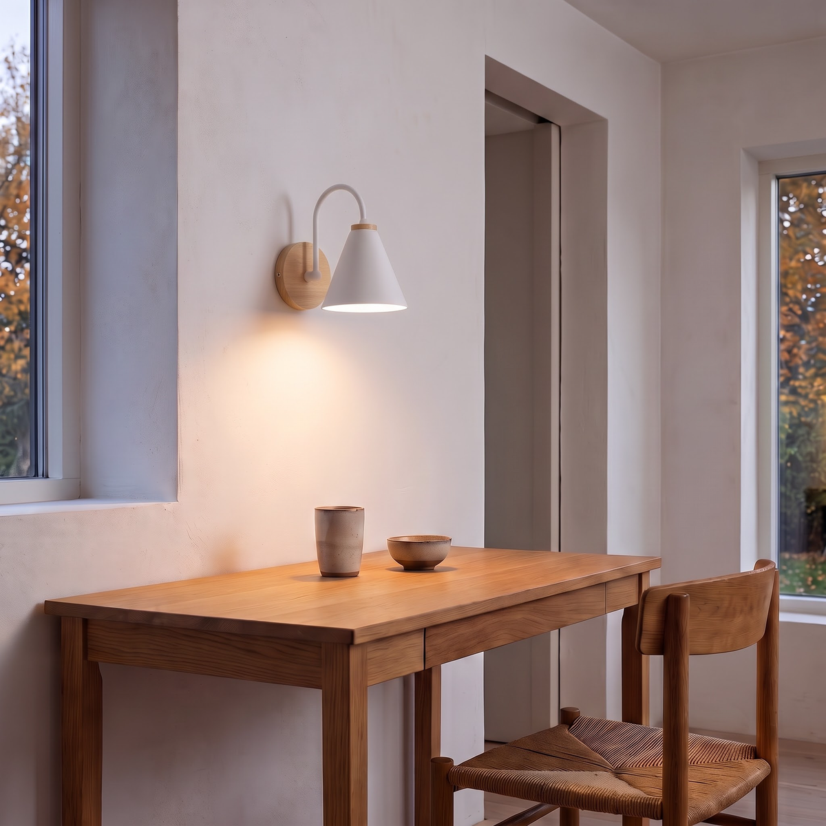 White gooseneck wall lamp above an oak writing desk in the evening