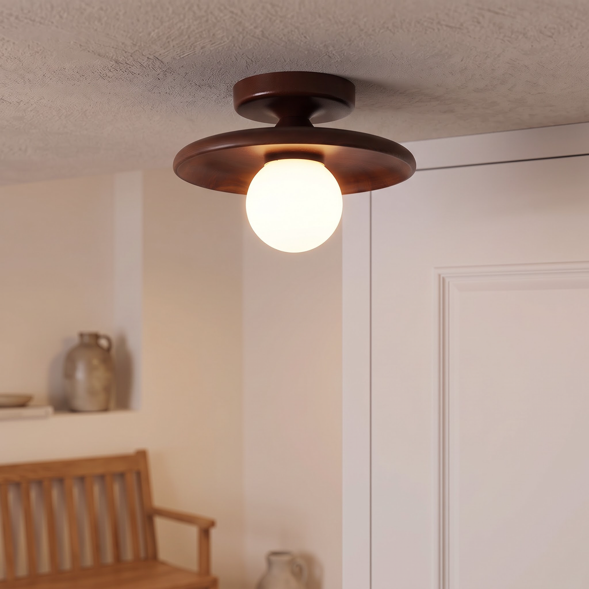 Walnut saucer ceiling light with opal globe glowing in an entry