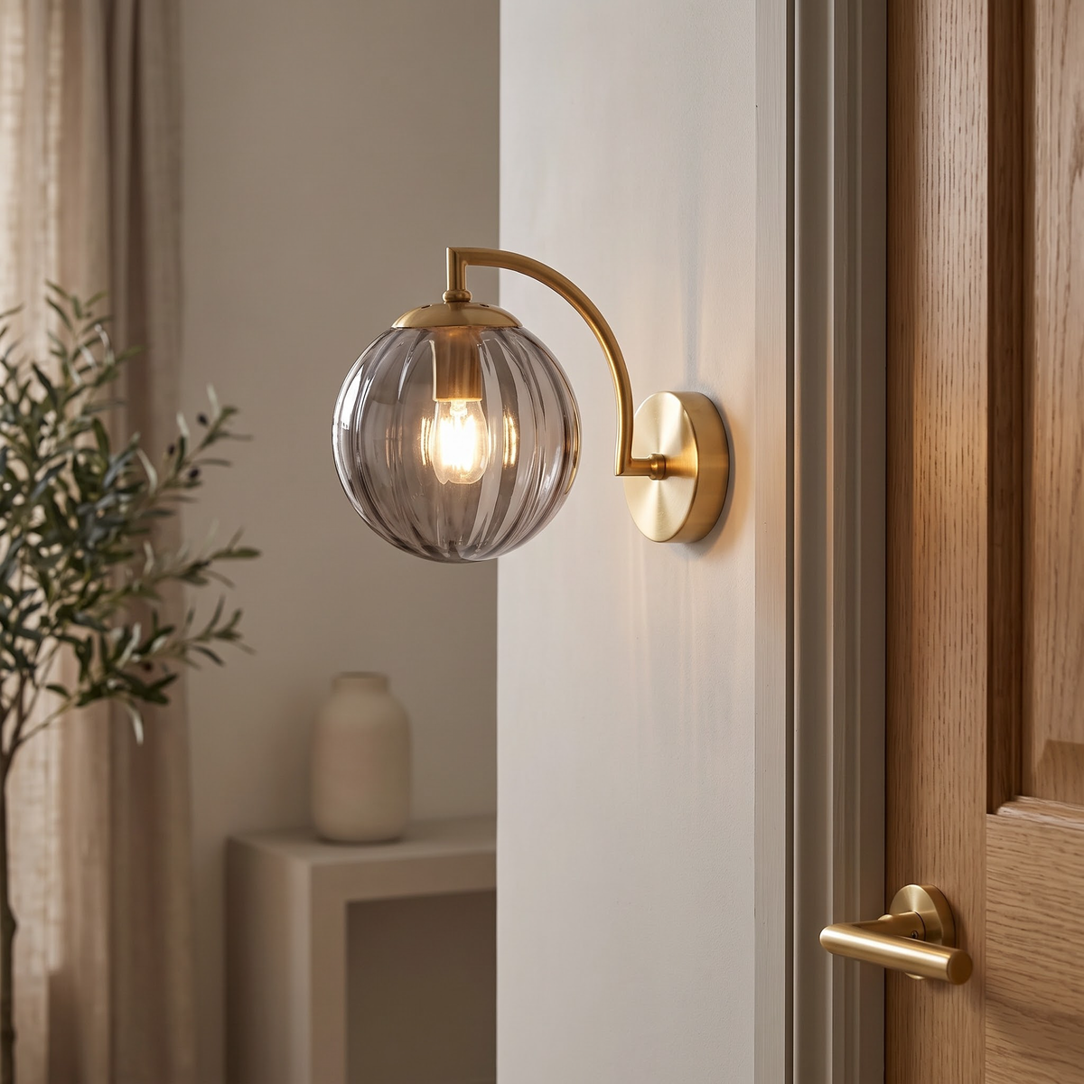 Smoke grey fluted glass globe wall sconce on a brass arm