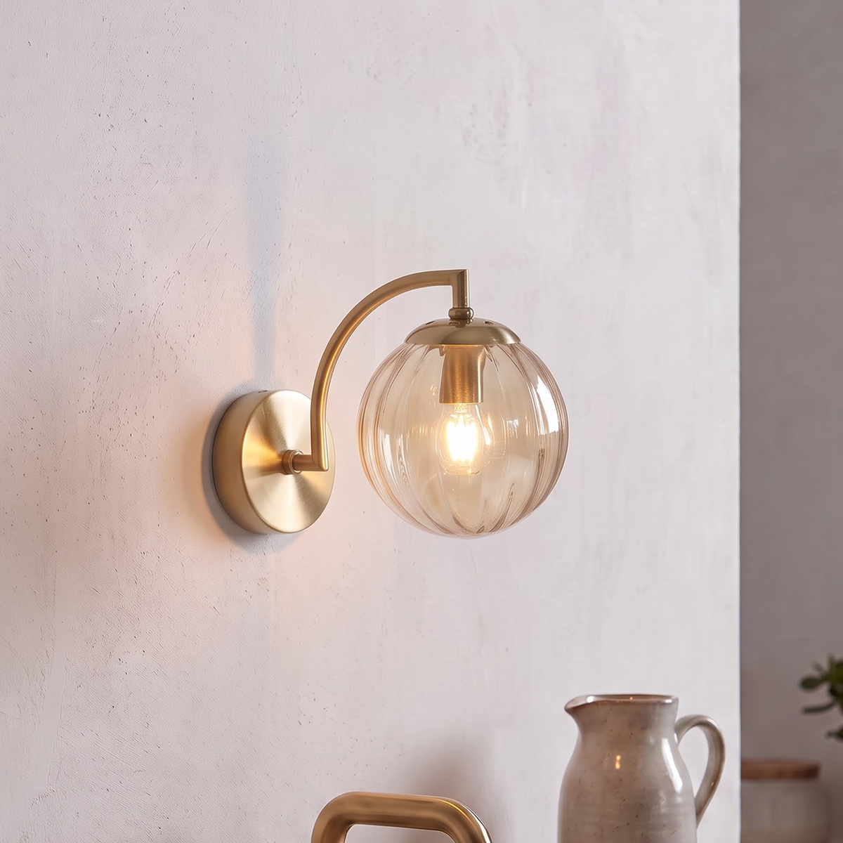 Champagne fluted glass globe sconce with brass arm in a bathroom