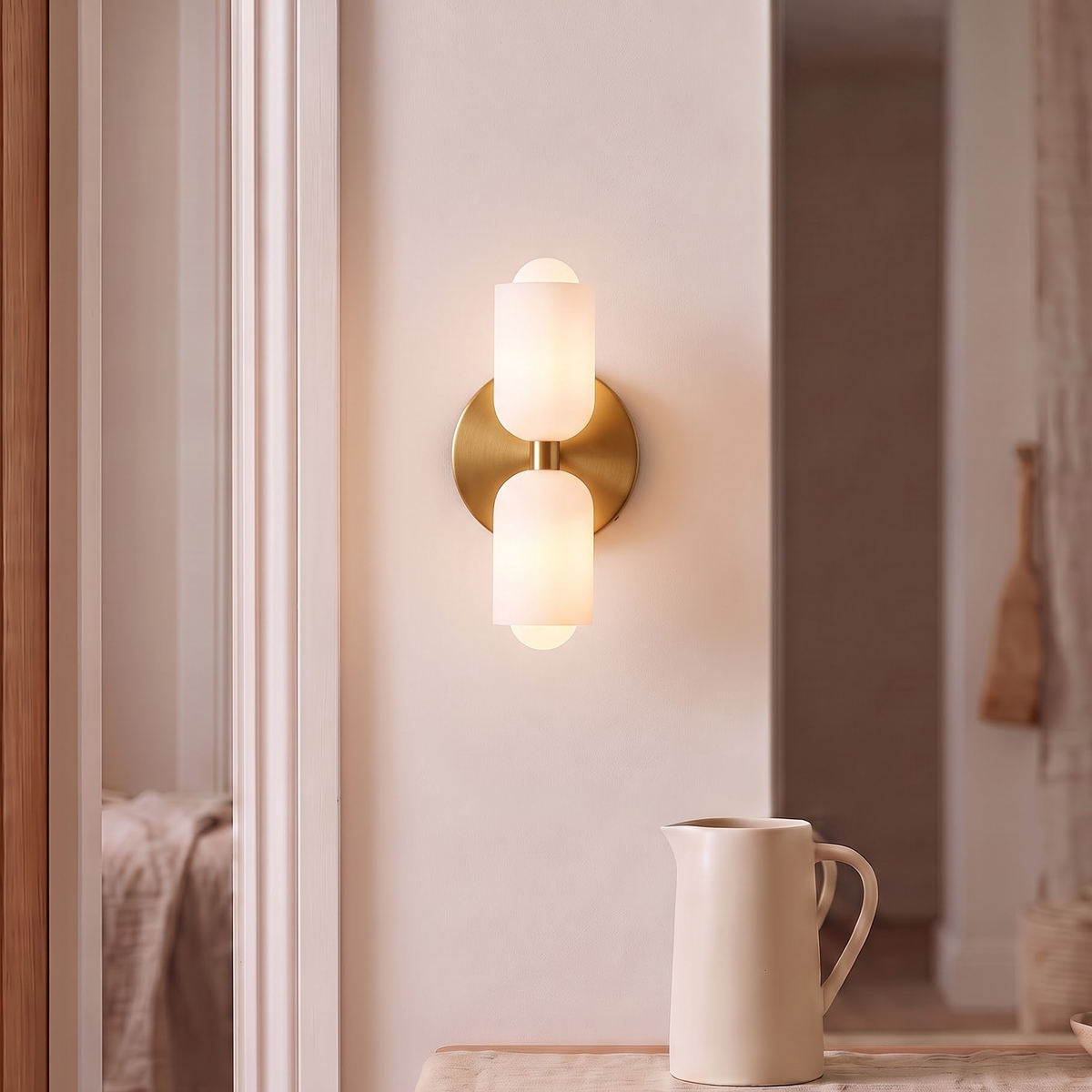 Gold double capsule wall sconce glowing above a walnut sideboard