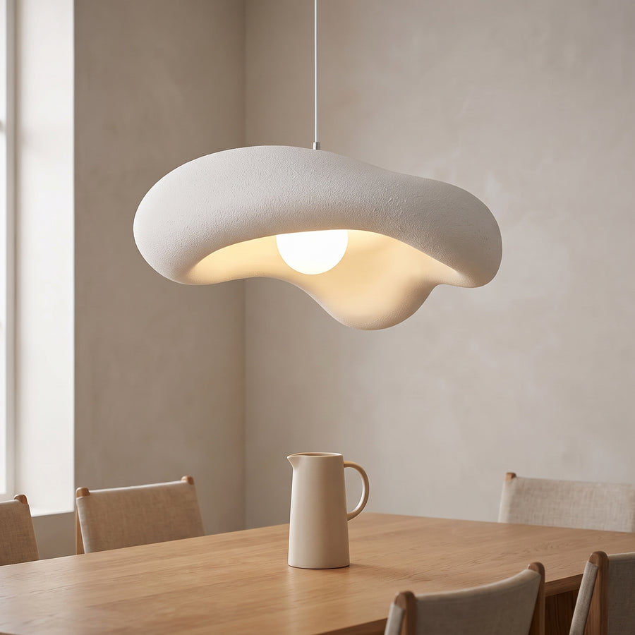 White textured cloud pendant light glowing over an oak dining table