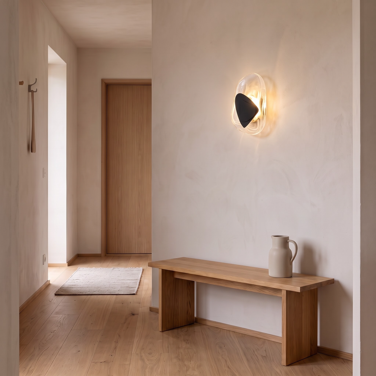 Swirled glass wall sconce with black plate in a calm hallway