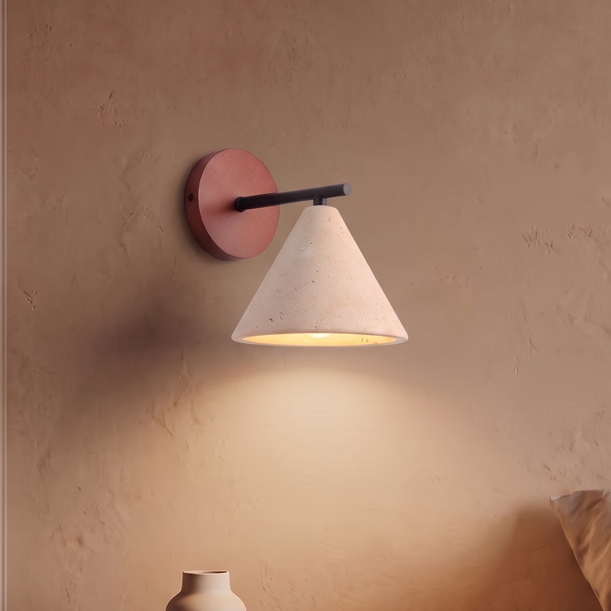 Travertine cone wall light on a terracotta backplate above a nightstand