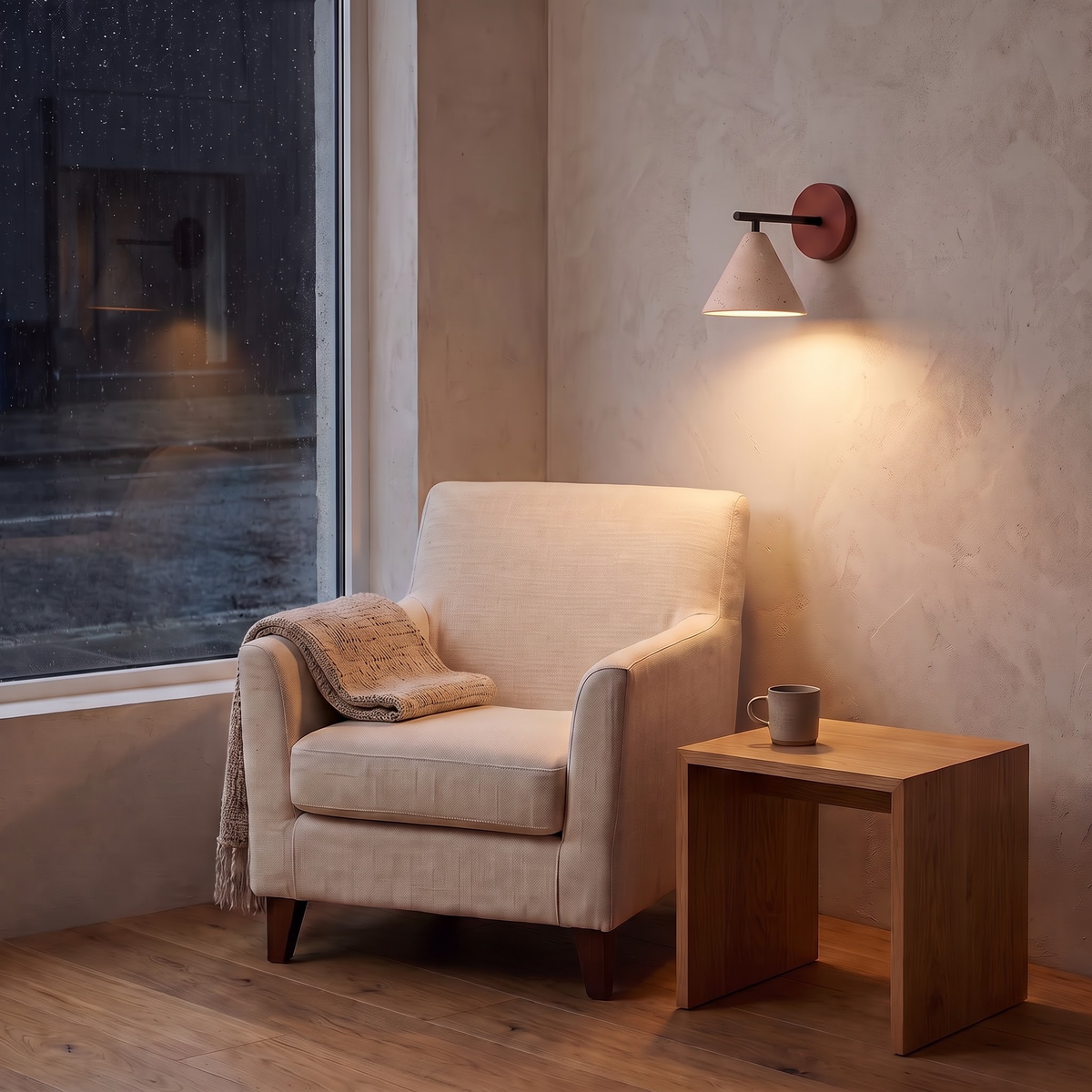 Pitted travertine cone wall light beside a linen reading chair